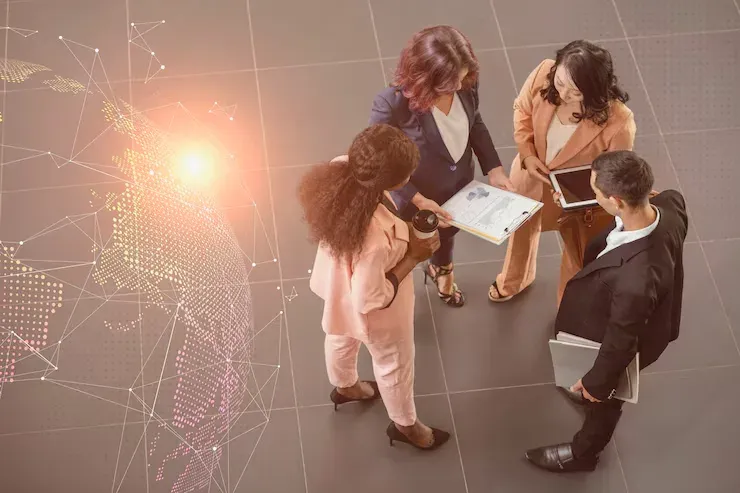 Four business colleagues talking beside a glowing digital globe network graphic