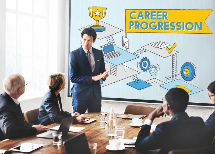 Man presenting a career progression diagram to colleagues in a meeting room