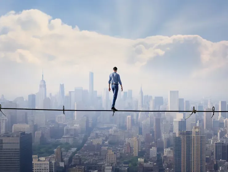 Man walking a tightrope high above a city skyline