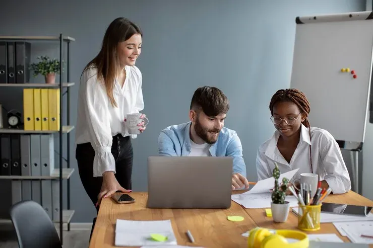 Three colleagues working together around a laptop in an office
