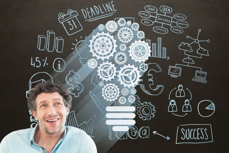 Smiling man beside chalk drawings of a gear light bulb, deadline and success